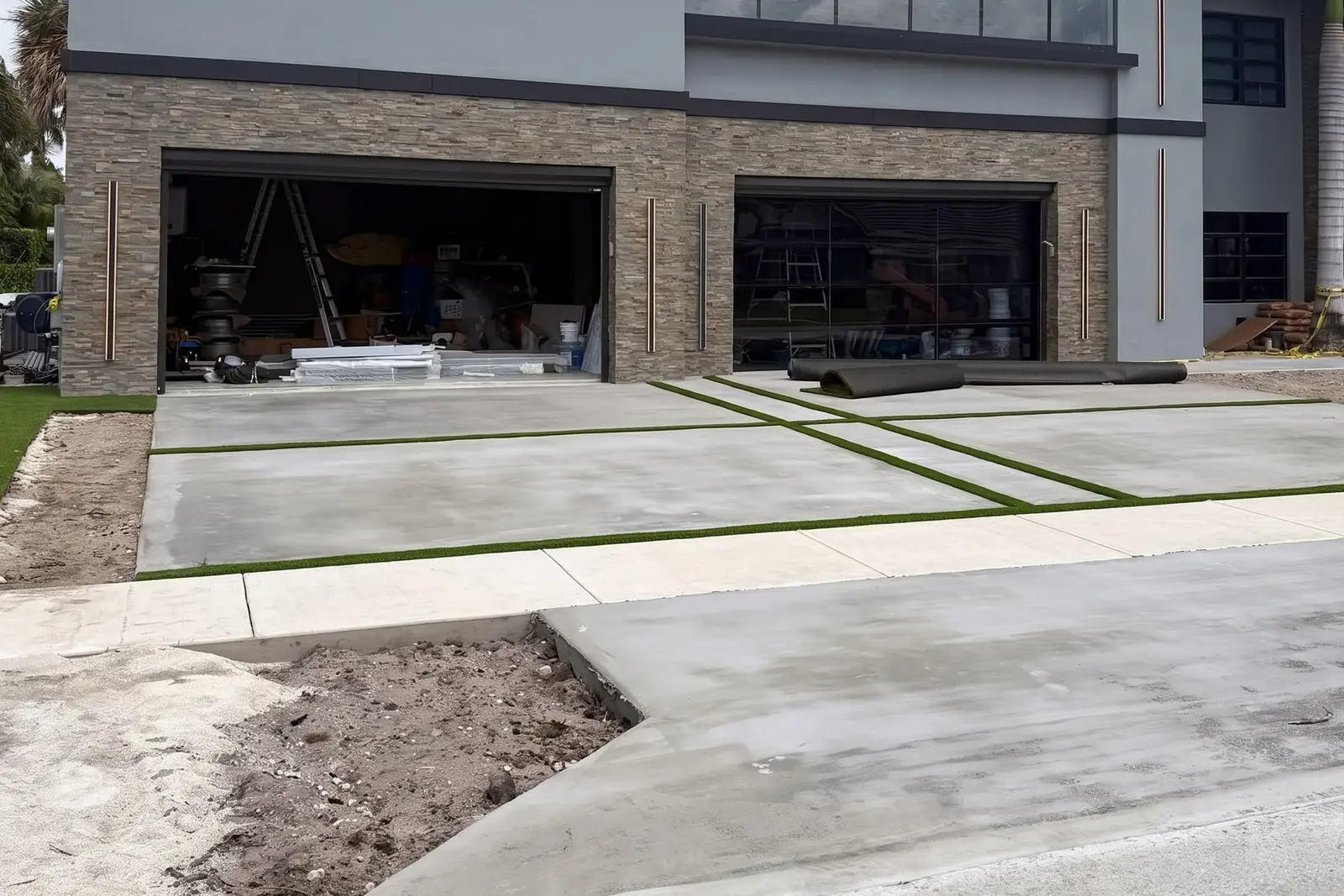 Two-story modern home with stacked-stone cladding, two open garage bays and a new grass-joint driveway