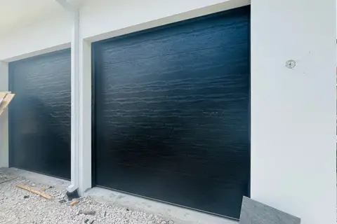 Two dark garage doors installed on a home still under construction