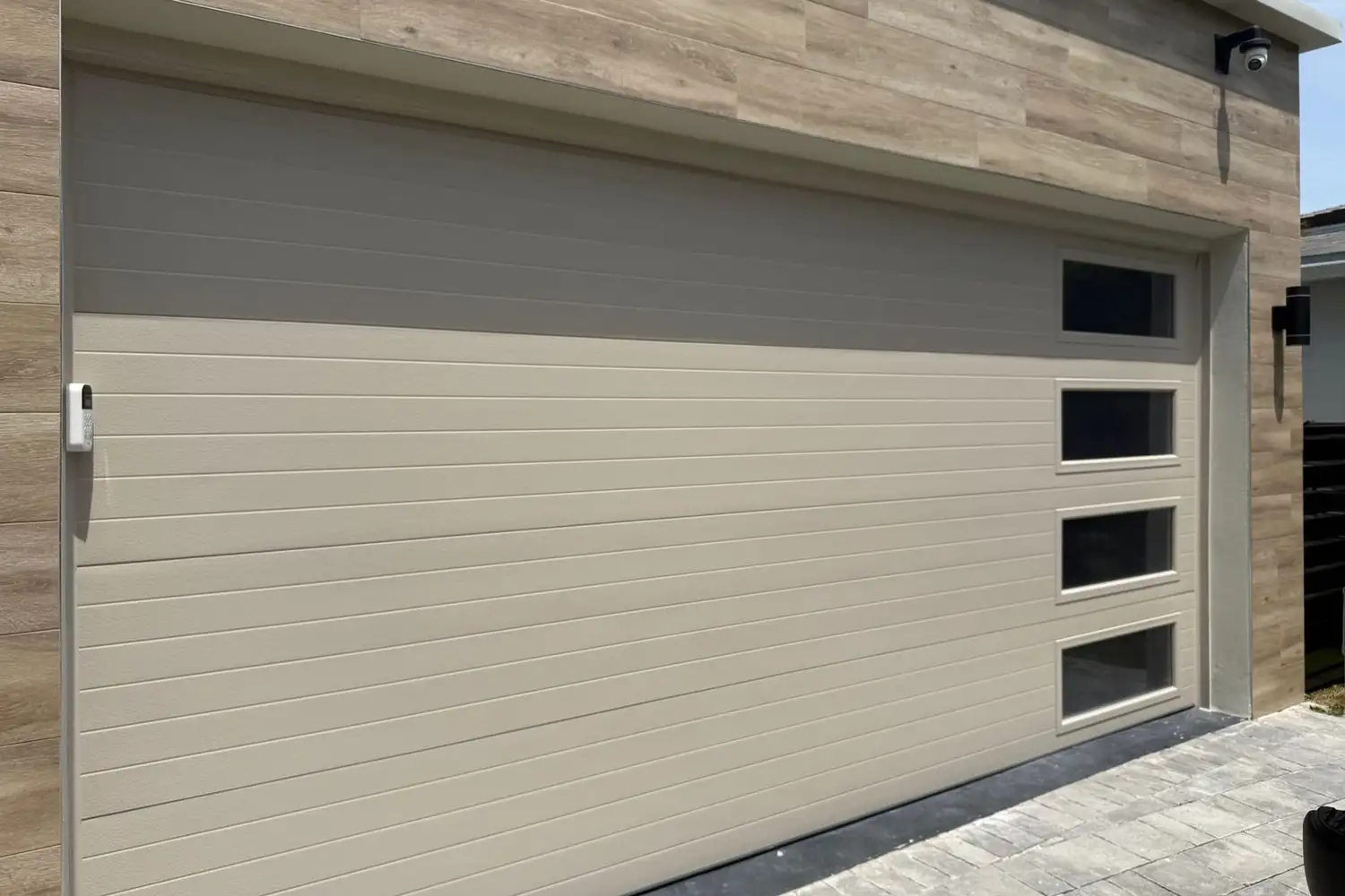 Sand-colored flush garage door with a column of windows, seen straight on