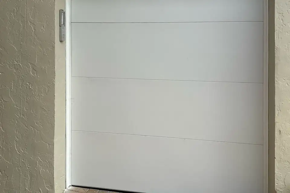 Plain white flush garage door set in a white stucco wall