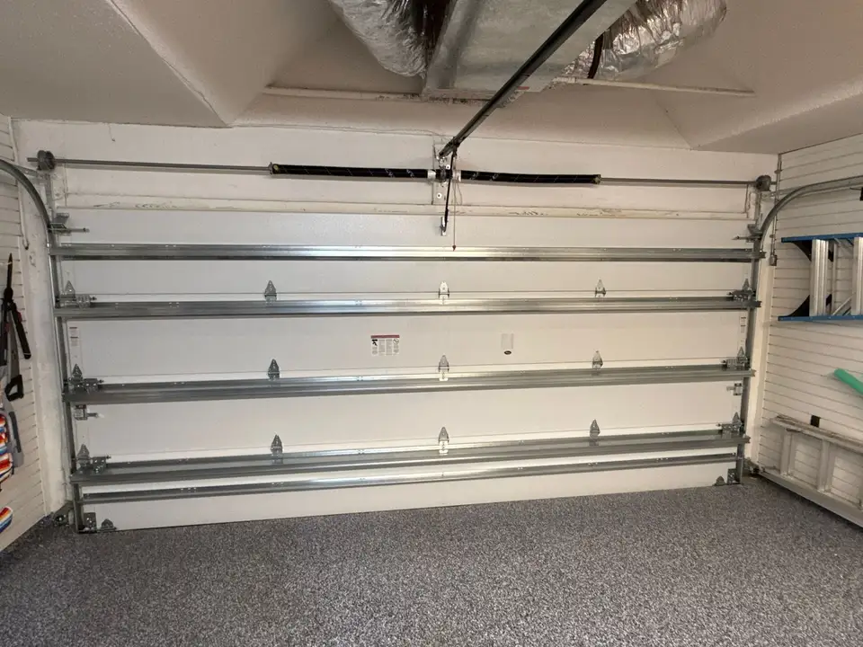 Garage interior with a white sectional door, its reinforcing struts and the opener rail overhead